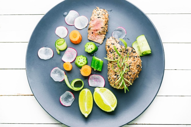 Bife de atum assado com guarnição de legumes. Peixe cozido com legumes.