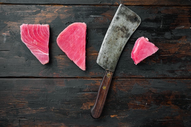 Bife de atum cru, conjunto de filé de atum vermelho fresco e velha faca de cutelo de açougueiro, na velha mesa de madeira escura