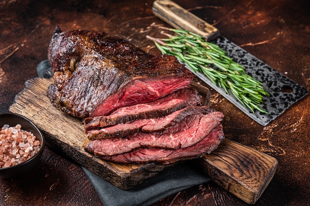 Bife de carne assada pendurada ou fatiada Onglet em uma tábua de açougueiro com cutelo. Vista do topo.