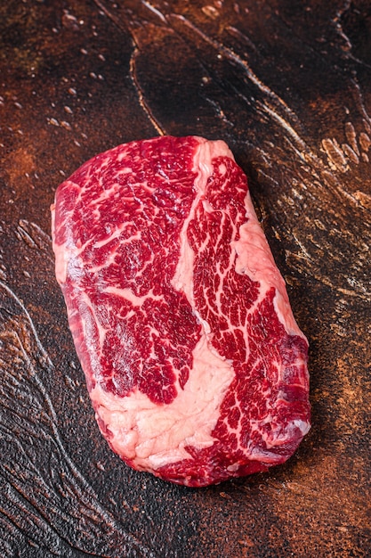 Bife de carne bovina de olho de costela crua em uma mesa de açougueiro preparada para cozinhar na mesa de madeira. Vista do topo.