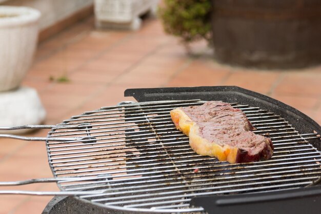 Bife de carne cozinhando na churrasqueira carvão para cozinhar carne crua refeição tradicional ao ar livre de domingo