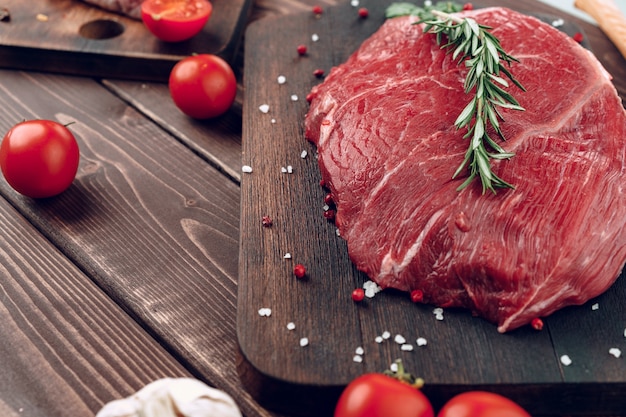 Bife de carne crua com alecrim e especiarias na tábua de madeira