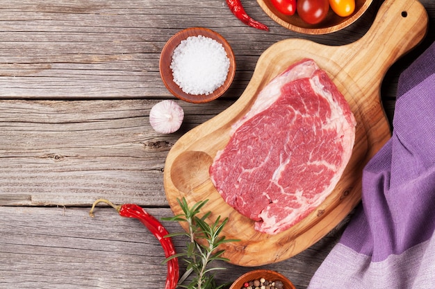 Bife de carne crua e especiarias na mesa de madeira