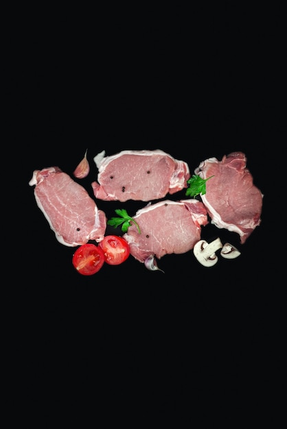 Bife de carne crua em fundo escuro com salsa alho champignons tomate vista superior