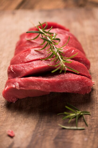 Bife de carne crua em uma mesa de madeira escura.