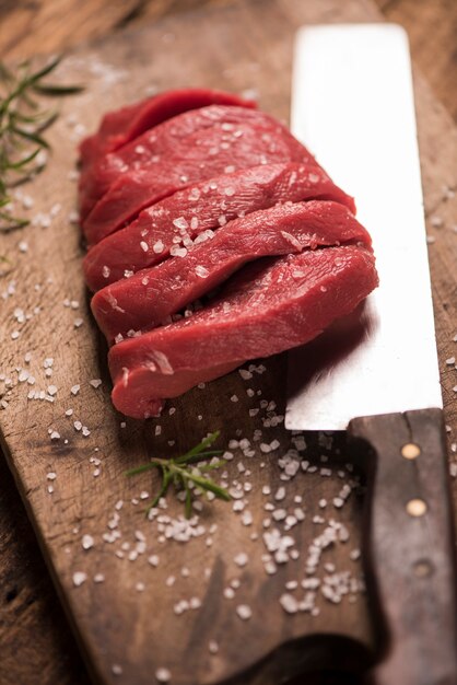 Bife de carne crua em uma mesa de madeira escura.