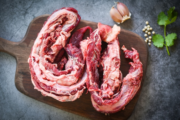 Bife de carne crua para churrasco com alho especiarias na tábua de madeira e fundo preto