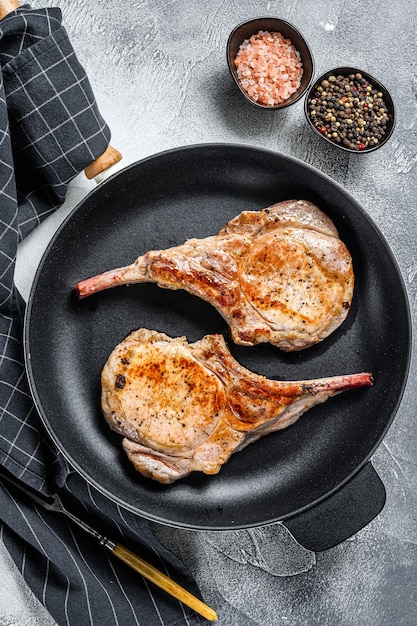 Bife de carne de porco frito tomahawk em uma panela. Fundo branco. Vista do topo.