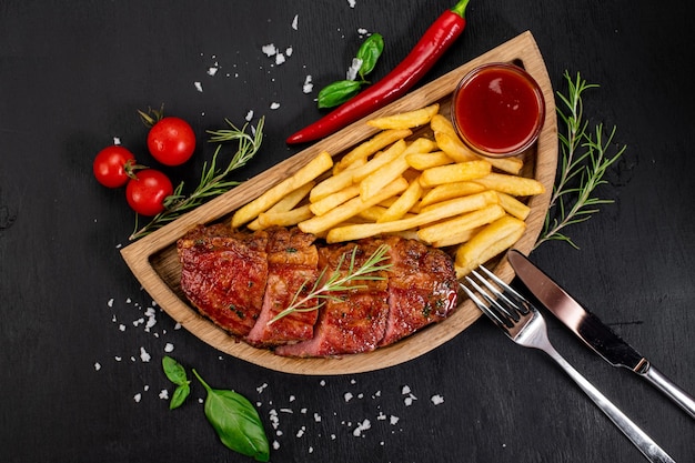 Bife de carne frita com batatas fritas e ketchup em fundo de madeira