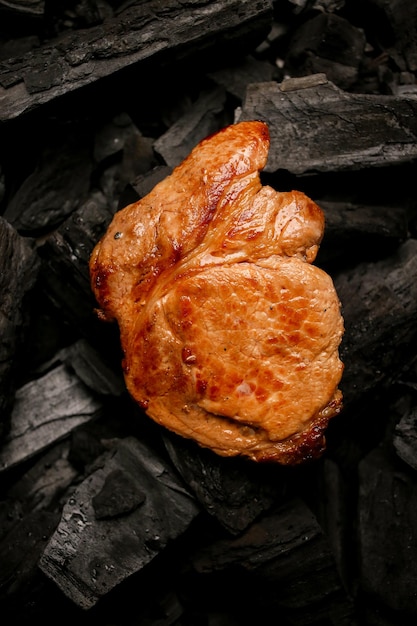 Bife de carne frita em um fundo preto de carvão Bife suculento cozido nas brasas