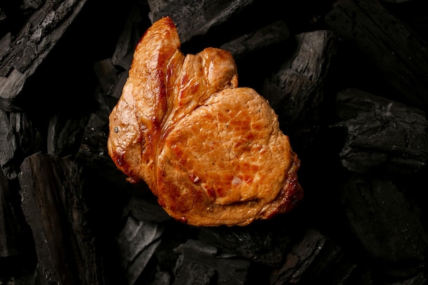 Bife de carne frita em um fundo preto de carvão Bife suculento cozido nas brasas