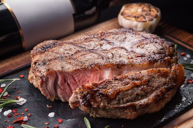 Bife de carne médio, em uma placa de pedra com uma garrafa de vinho