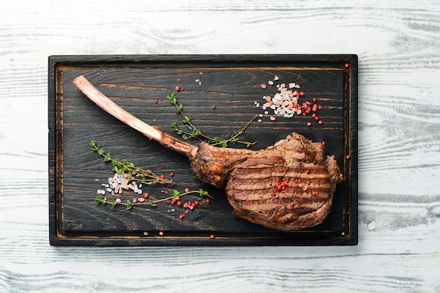 Bife de carne tomahawk envelhecido seco com ingredientes em um fundo de pedra preta Vista superior com espaço livre para cópia