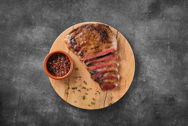 Bife de coração de carne grelhada com pimenta em uma placa de madeira