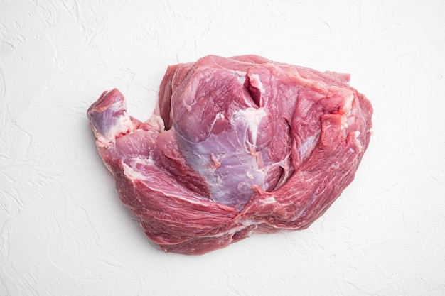 Bife de costeleta de porco crua. Pedaço de carne crua pronto para o conjunto de preparação, no fundo da mesa de pedra branca, vista de cima plana lay