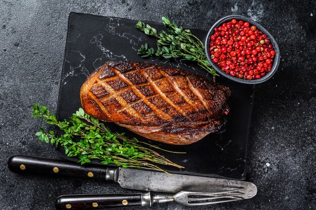 Bife de filé de peito de pato assado no natal. fundo preto. vista do topo.