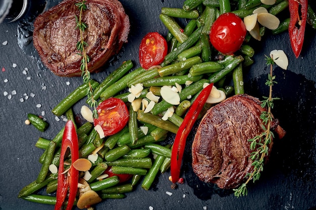 Bife de filé mignon com enfeite vegetal em uma placa preta. Close-up, foco seletivo