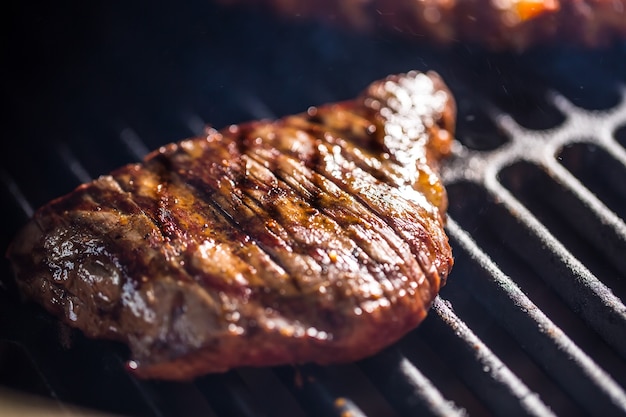 Bife de flanco de carne de close-up cozinhando na grelha.