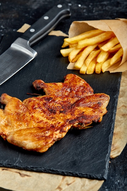 Bife de frango com batatas fritas em um espaço preto