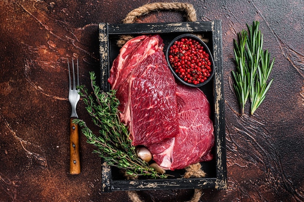 Bife de lombo cru em bandeja de madeira com ervas