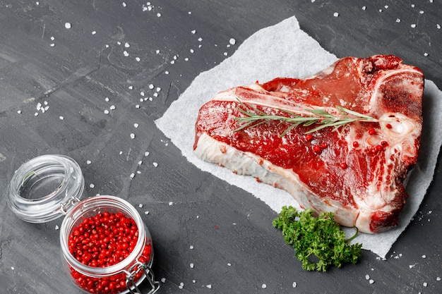 Bife de lombo de carne crua com especiarias em uma mesa escura, close-up