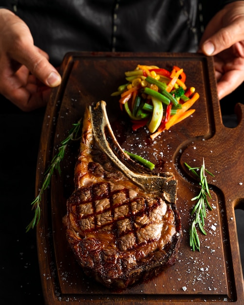 Bife de lombo de osso longo cozido Tomahawk em uma placa de servir