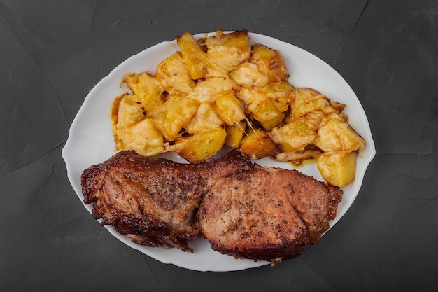 Foto bife de lombo de porco e batatas assadas com queijo em um prato branco