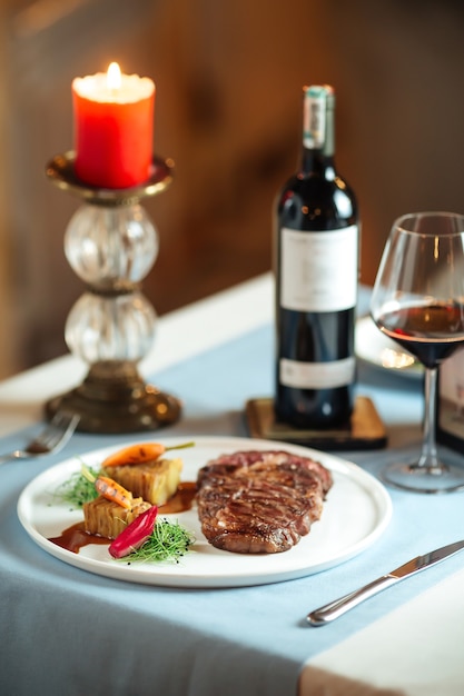 Bife de lombo de vaca grelhado com batatas no prato branco com vinho tinto