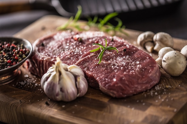 Bife de olho de costela sal pimenta especiarias alho e cogumelo. carne de bovino crua no açougue.