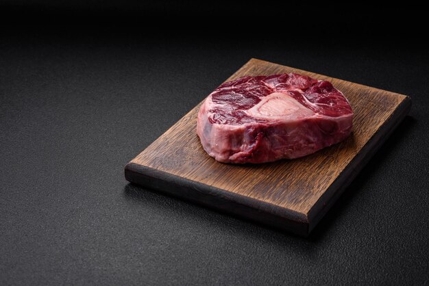 Bife de ossobuco de carne fresca com especiarias salgadas e ervas em fundo de concreto texturizado