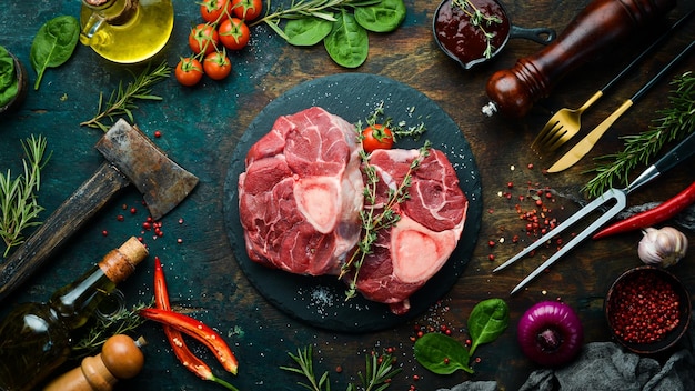 Bife de Ossobuko de carne fresca no osso com alecrim e especiarias Em um fundo de pedra preta Vista superior