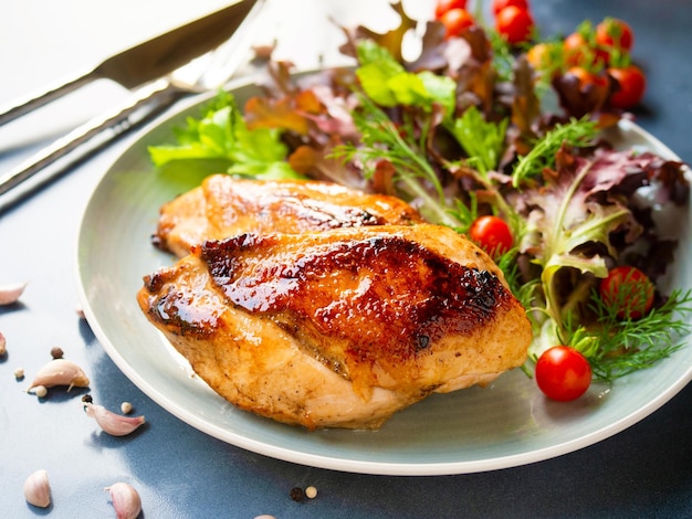 Bife de peito de frango grelhado serve com tomate cereja fresco e salada em um prato de cor cinza