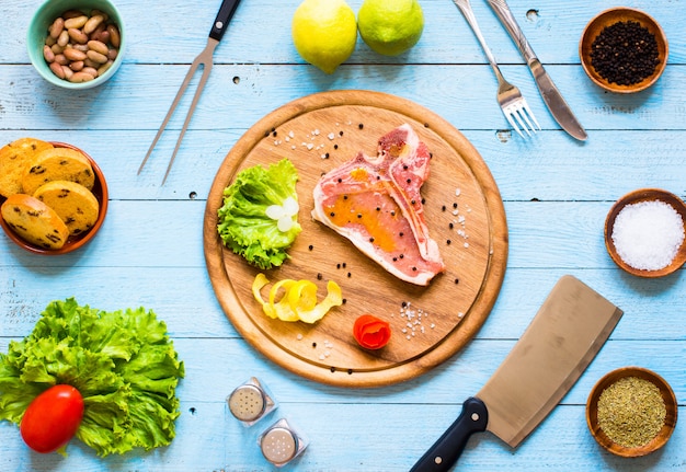 Bife de porco caseiro de cozinhar com especiarias folhas de alface na tábua de madeira e um prato,