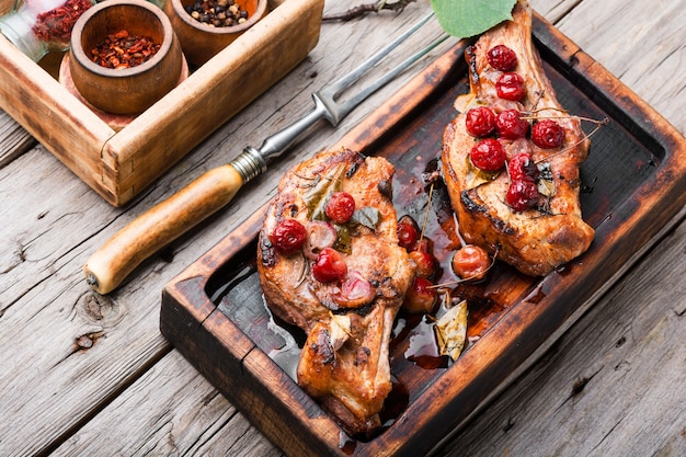 Bife de porco com osso assado em marinado de frutas vermelhas. Carne com molho de cereja