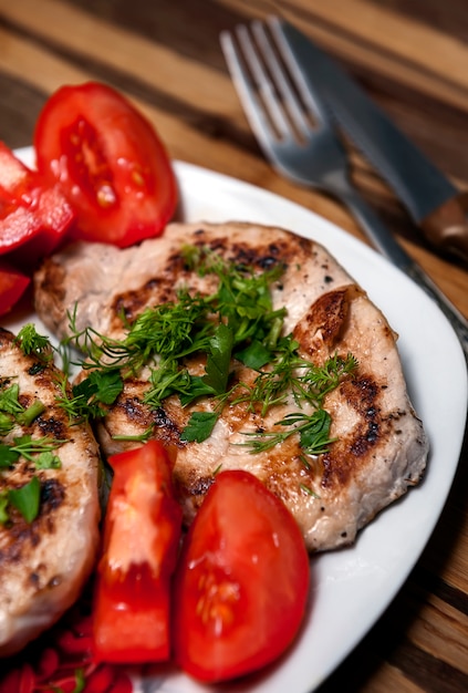 Bife de porco com tomates e ervas frescas.