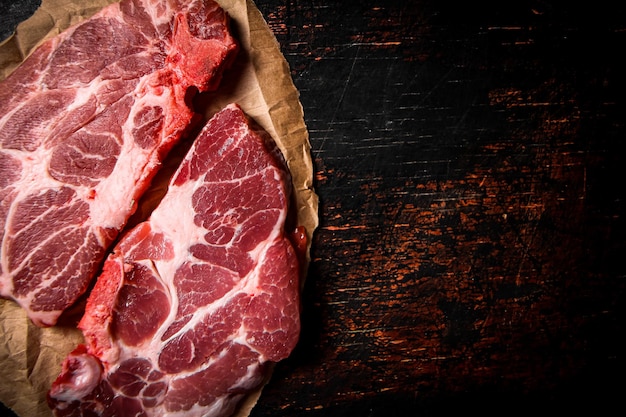 Bife de porco cru em papel em cima da mesa