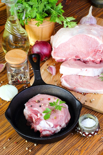 Bife de porco cru em uma frigideira na mesa da cozinha