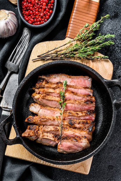 Bife de porco em mármore fatiado frito em uma panela.