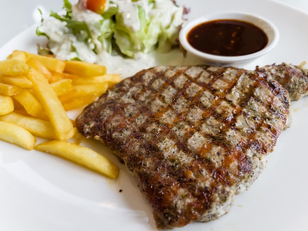 Foto bife de porco grelhado com batatas fritas