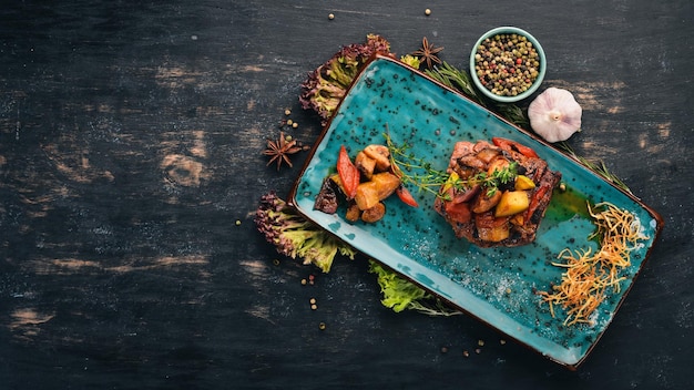 Bife de porco grelhado com legumes Aperitivos quentes Vista superior Em um fundo preto de madeira Copie o espaço