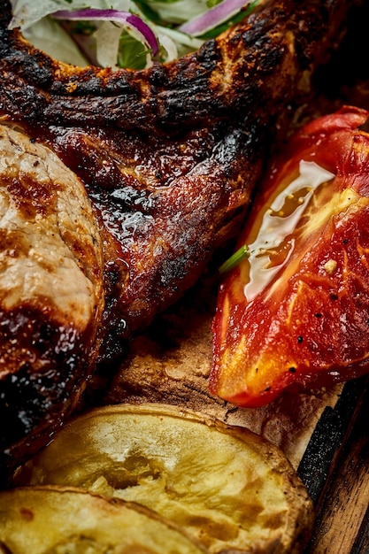 Foto bife de porco no osso assado com legumes em uma placa de madeira close-up