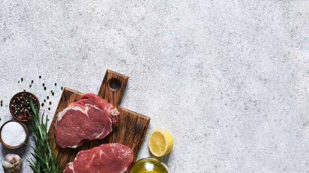 Bife de ribeye cru cozinhando com ingredientes: sal, pimenta, limão. vista superior com espaço de cópia