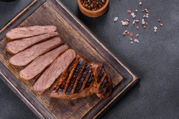 Bife de rolo de olhos de Chuck grelhado cozido em uma tábua de cortar. Fundo escuro