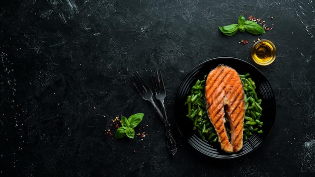 Bife de salmão assado com feijão verde em um prato preto Vista superior Espaço para cópia grátis