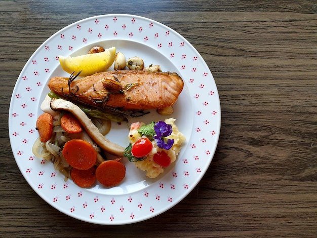 Bife de salmão assado com legumes grelhados e polenta no fundo de madeira