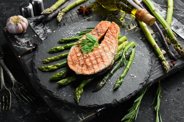 Bife de salmão com aspargos assados e especiarias em uma placa de pedra preta Vista superior Espaço livre para o seu texto