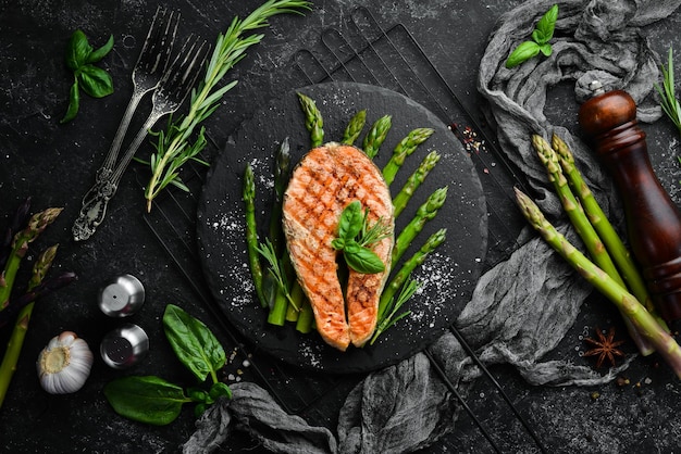 Bife de salmão com aspargos assados e especiarias em uma placa de pedra preta vista superior espaço livre para o seu texto