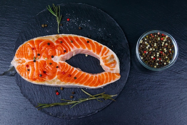 Bife de salmão cru com especiarias na vista superior de ardósia preta