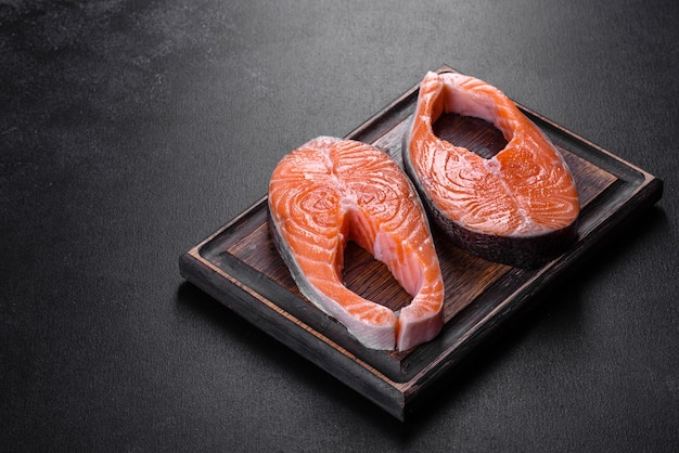 Bife de salmão cru fresco com especiarias e ervas preparadas para assar na grelha. Comida saudável de frutos do mar