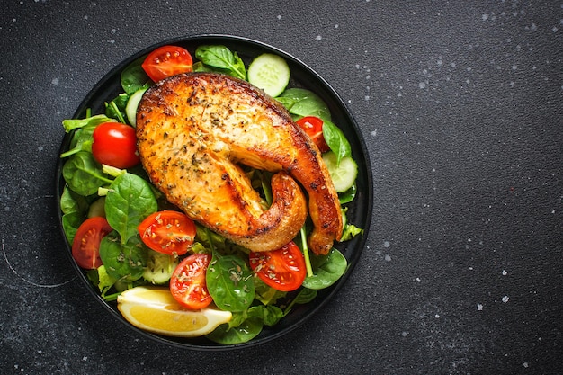 Bife de salmão e salada verde fresca em fundo preto Dieta Keto comida saudável Vista superior espaço de cópia